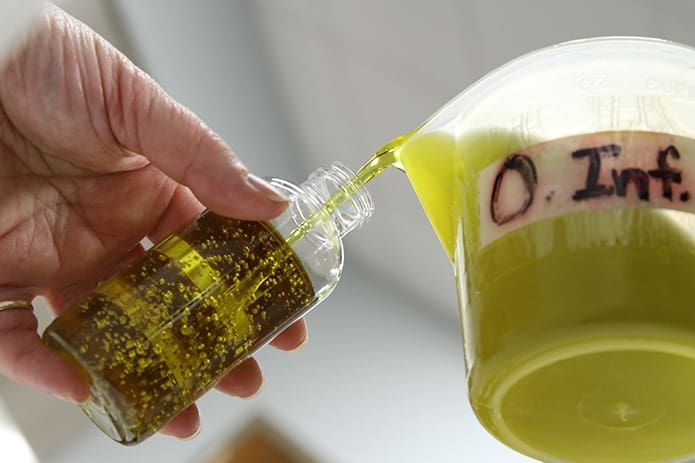 Cathedral of Christ the King parishioner Janey Wilcox pours the oil of the sick into plastic bottles for the archdiocesan parishes. Wilcox has been a member of the cathedral’s Chrism Mass oil distribution team for over 20 years. Photo By Michael Alexander.