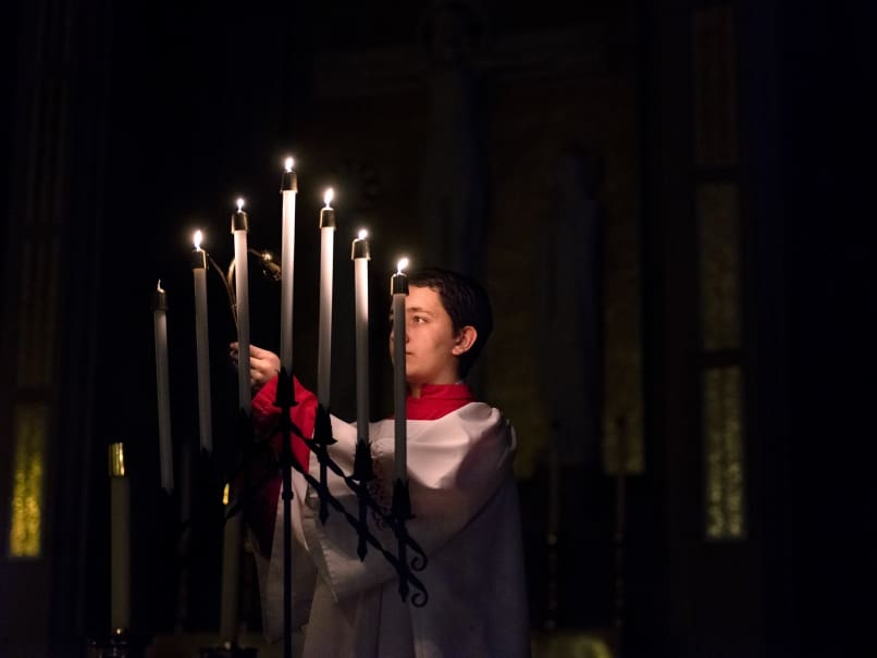 An altar server lights the candles during a Tenebrae service at Cathedral of Christ of the King. Tenebrae is a solemn prayer service of song and ure, marked by the gradual extinguishing of lights until the service ends in darkness and silence. Photo by Johnathon Kelso