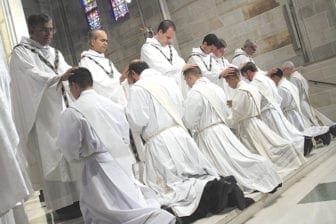 Archdiocesan and visiting priests lay hands upon the seven ordination candidates during their June 8 ordination to the priesthood at the Cathedral of Christ the King, Atlanta. (Photo by Michael Alexander)