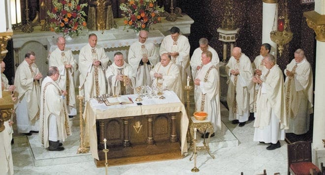 Joined by his fellow priests, Father Ted Keating, Marist provincial, raises the host and chalice during the Liturgy of the Eucharist.